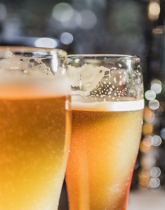 Light beer in a beer glass and dark beer in a small glass lighted with warm light close up